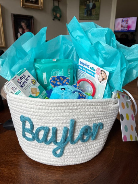 A gift basket with the name Baylor, filled with baby gifts and tissue paper