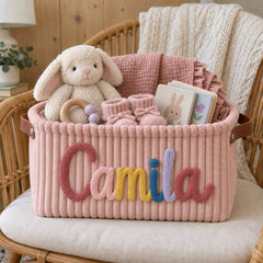 Pink corduroy basket with the name Camila in rainbow yarn